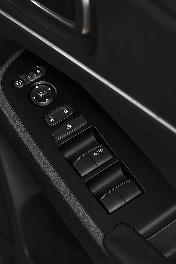 Close-up of a car's interior door panel featuring power window and mirror controls.