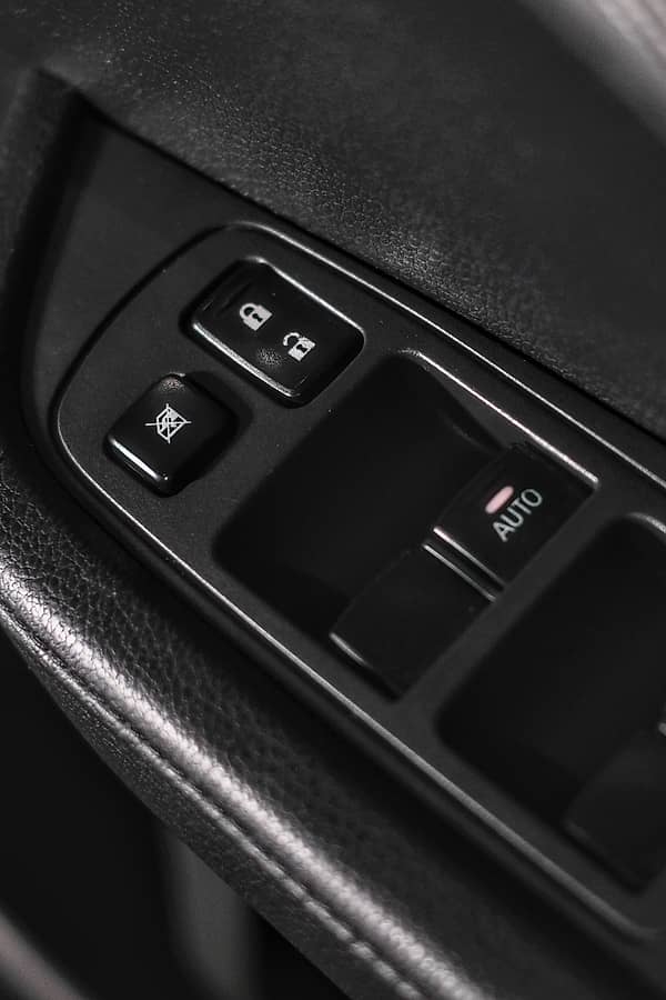 Close-up of a car's interior door panel showing electric window control buttons.