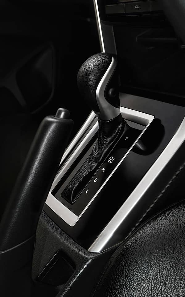 View of the central console in a car, featuring the automatic gear selector, parking brake, and part of the steering wheel.